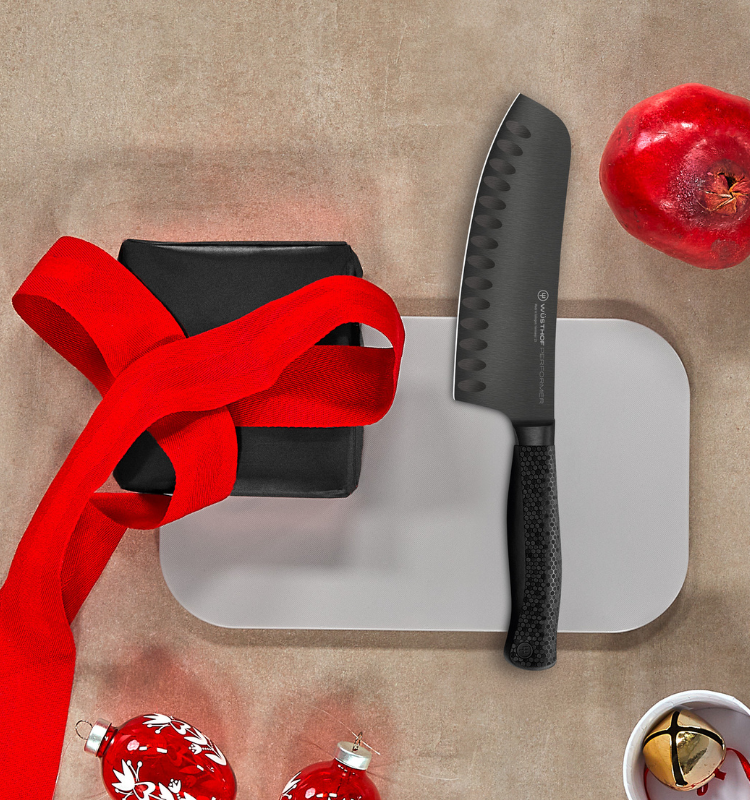 Black knife on a white cutting board with a red ribbon and pomegranate on a beige background