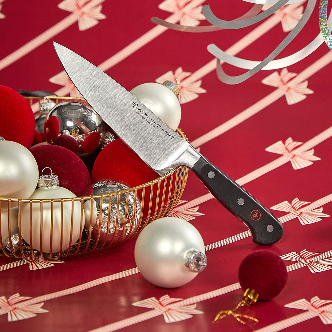 Knife with black handle on a red surface with Christmas ornaments