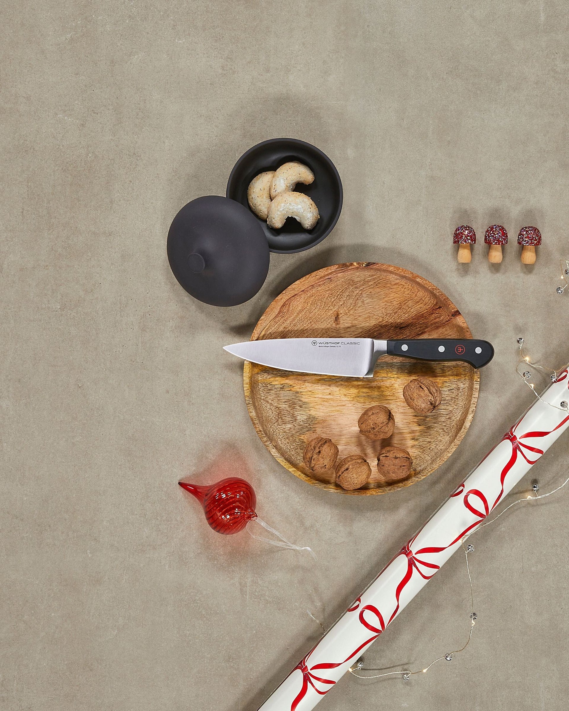 Wooden cutting board with knife, mushrooms, and a black bowl on a beige surface.