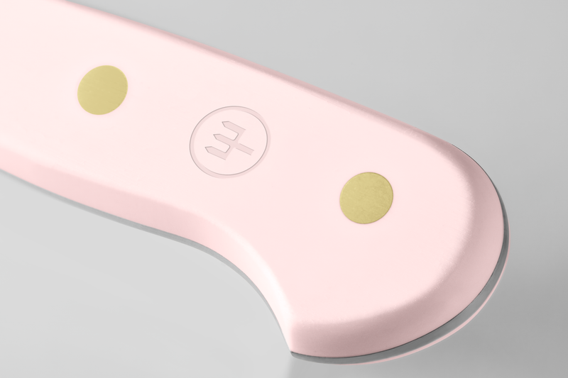 Close-up of a pale pink knife handle with two brass rivets and an embossed logo, highlighting smooth contours and sturdy construction.