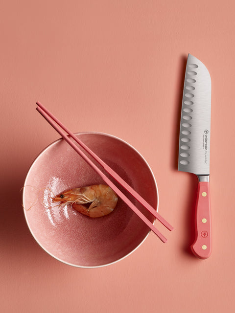 Coral peach hollow edge santoku near bowl with small fruit and chopsticks