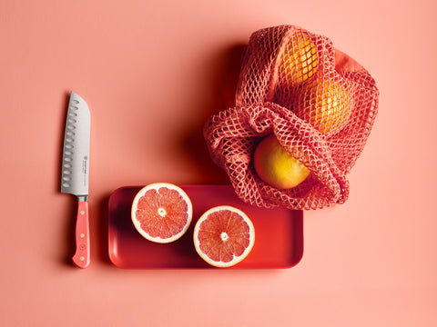 Coral peach hollow edge santoku near vibrant fruit and netted bag
