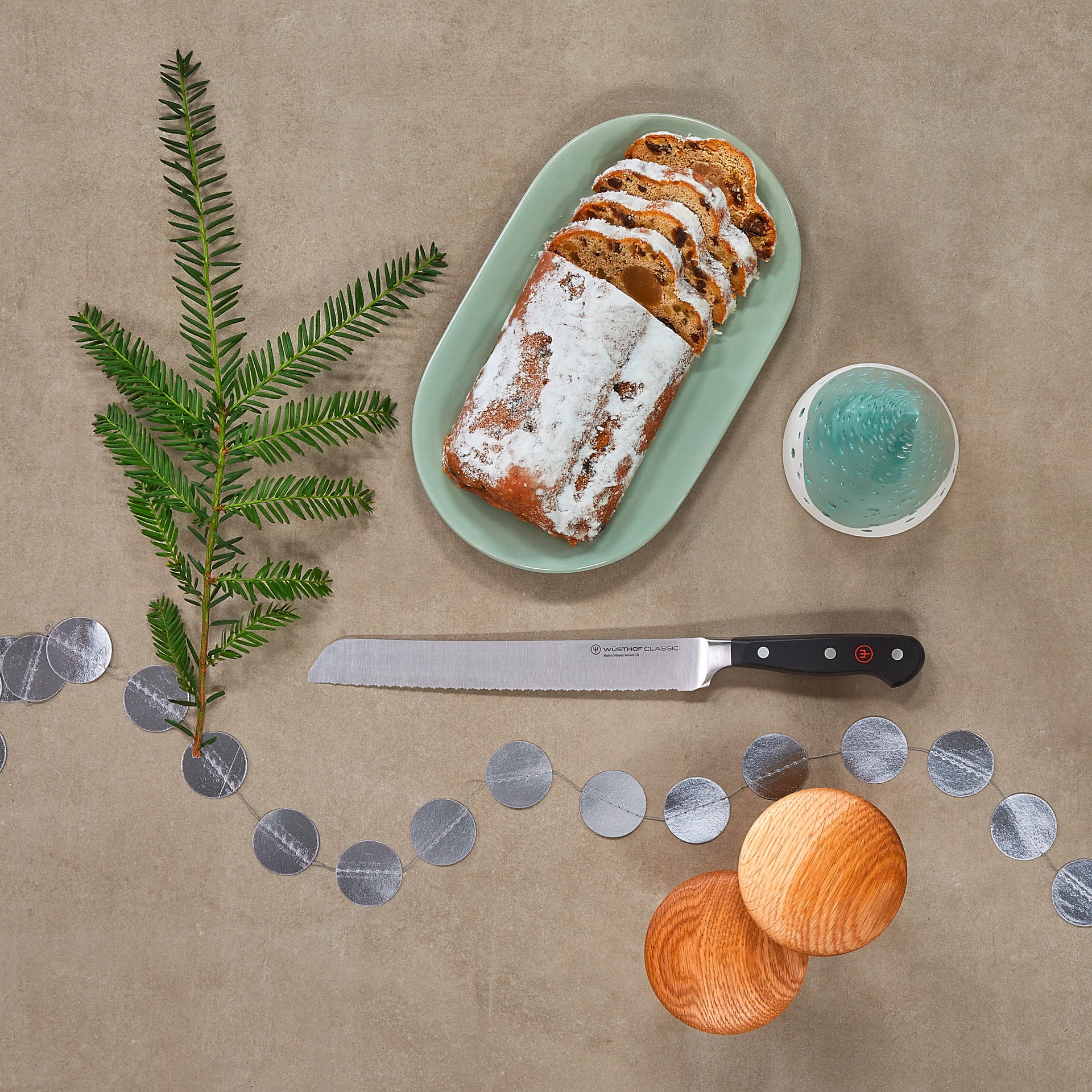 Loaf of bread with icing on a green plate, knife, and decorative elements on a brown background